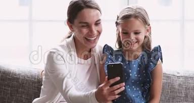 可爱的妈妈在智能手机上播放可爱的小女儿<strong>搞笑视频</strong>